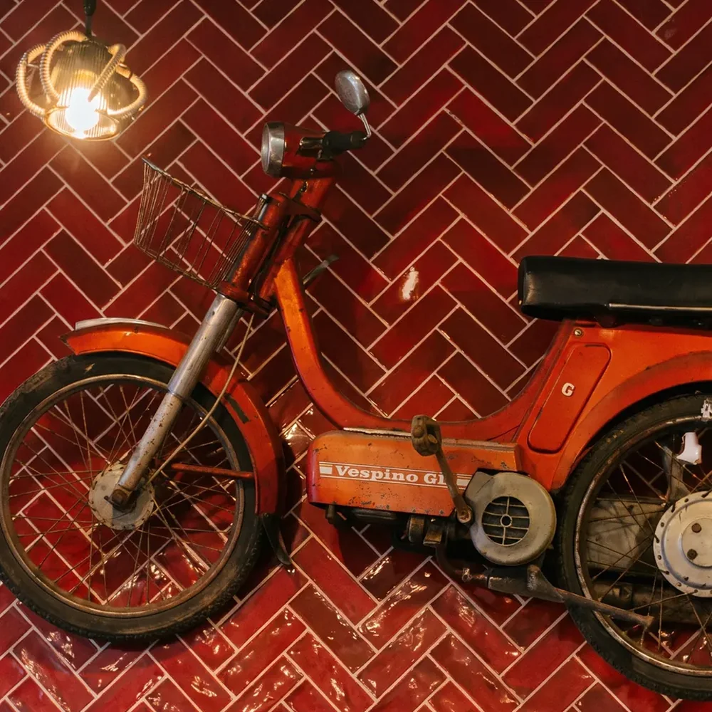 Red moped hanging on the herringbone brick wall at Mi Locura, Mairena del Aljarafe